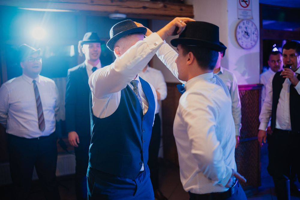People dancing and celebrating at a wedding reception with blue lighting and festive atmosphere.