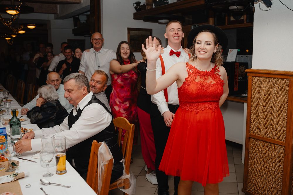 Wedding guests dancing and celebrating at a reception venue with bright red dresses and festive atmosphere.