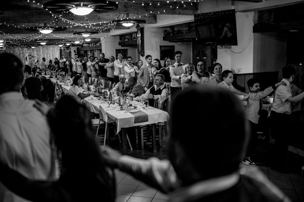Black and white photo of a crowded reception dinner event with guests seated at long tables under decorative lighting.