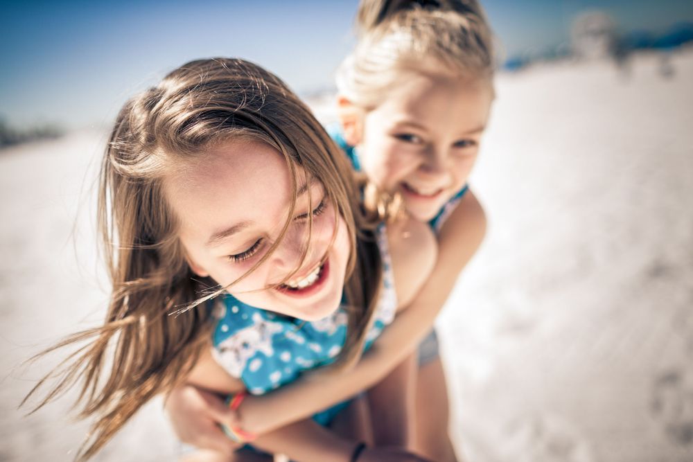 Two joyful people playing and laughing together on a sunny beach during summer.