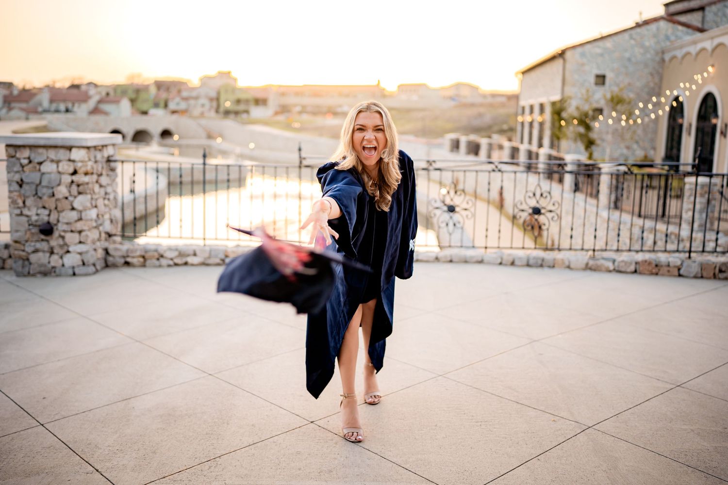 Person in a dark dress walking barefoot on a stone patio during golden sunset light at a luxury resort.