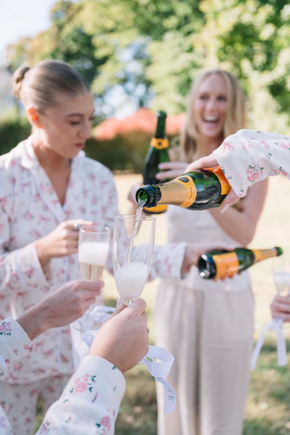Celebratory moment of pouring champagne into glasses outdoors during a special occasion.