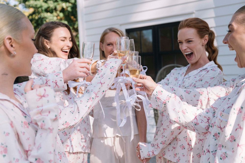 A group celebrating in matching floral robes raising champagne glasses for a toast.