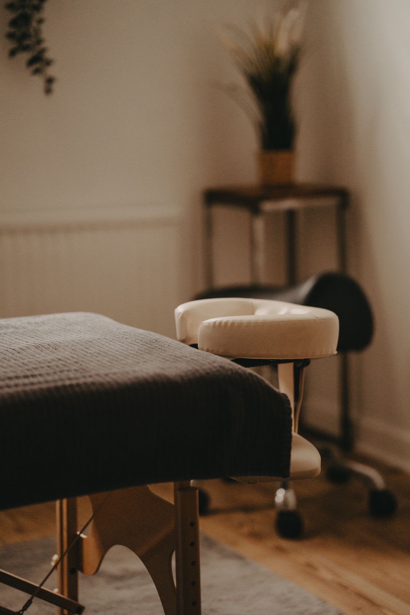 A professional massage table in a serene spa room with hardwood floors and minimalist decor.