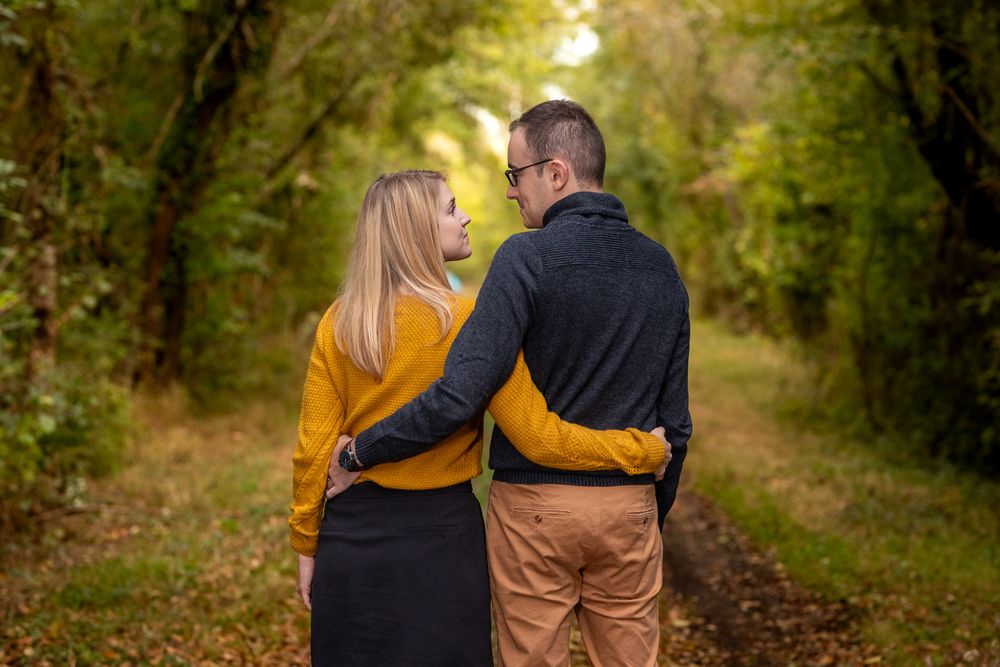Romantic stroll along a tree-lined path during golden hour with warm autumn colors.