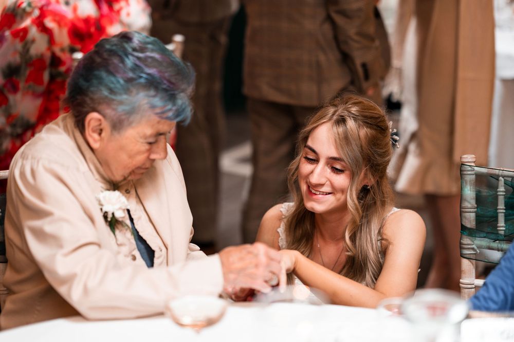 A heartwarming candid moment between a happy bride and an elderly guest during a wedding celebration.