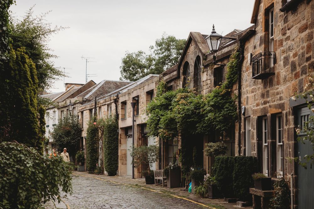 A charming cobblestone street lined with historic stone buildings and climbing ivy in Edinburgh's Circus Lane.