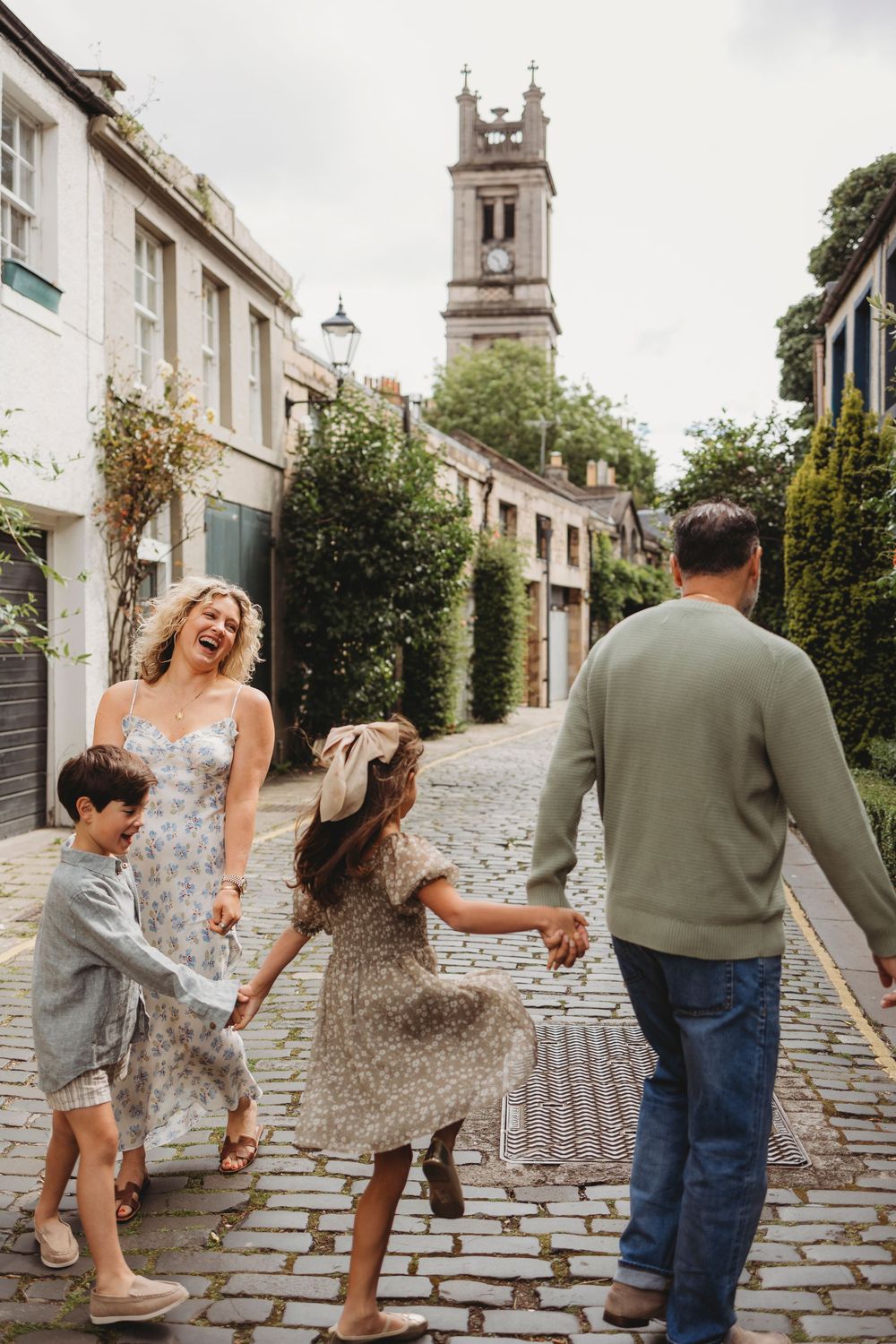 A family enjoying a joyful moment on a cobblestone street with a historic church tower in the background.