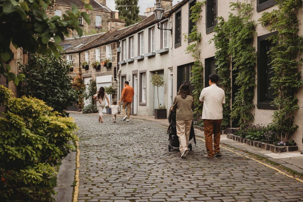 People walking along a cobblestone street in Edinburgh's historic Circus Lane with traditional Georgian terraced houses.
