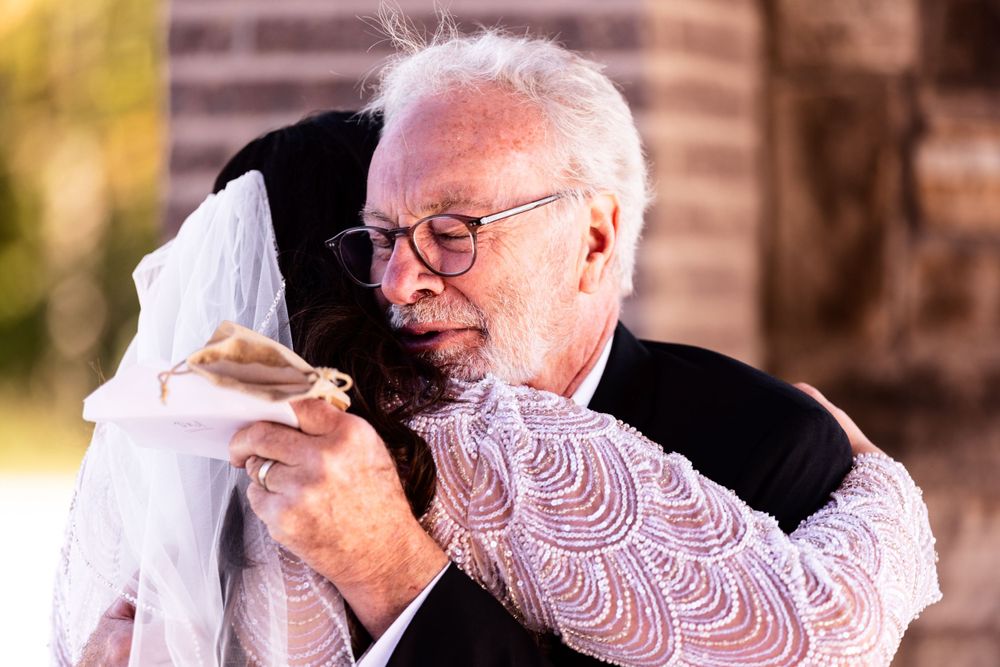 An emotional moment captured at a wedding as an elderly person embraces someone in white.