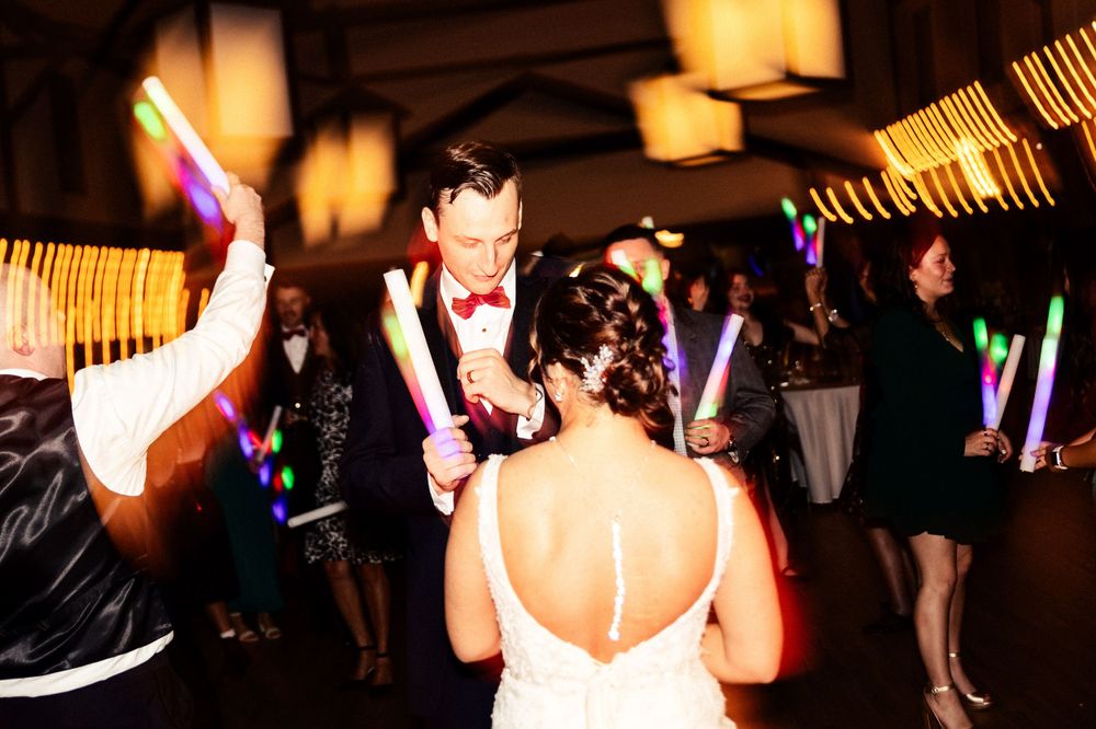 Wedding reception dance party with glowing light sticks creating a festive atmosphere.