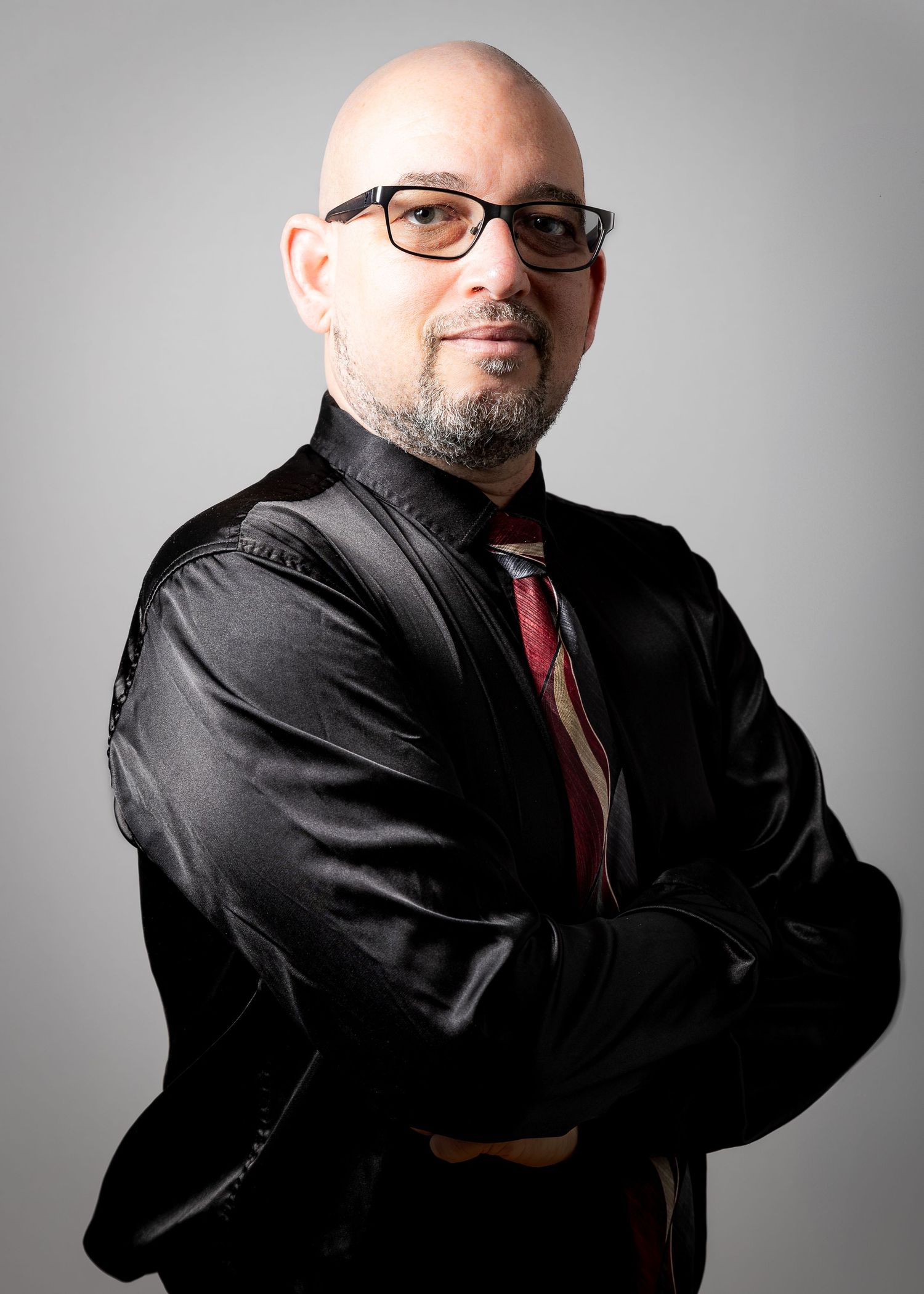 Professional headshot series of a male in black attire and red tie against a light gray background from multiple angles.