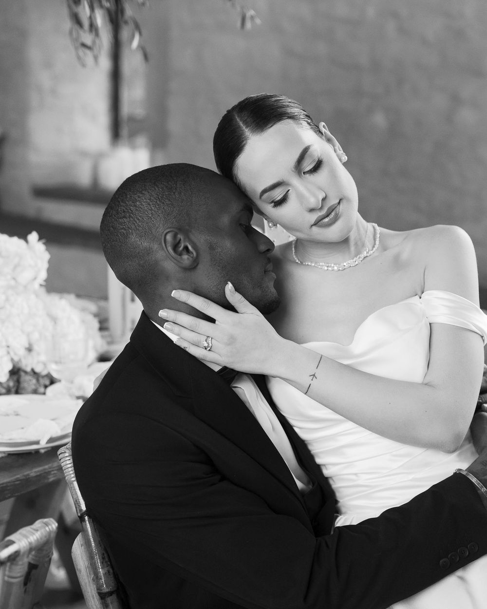 Intimate black and white wedding portrait capturing tender moment between newlyweds.