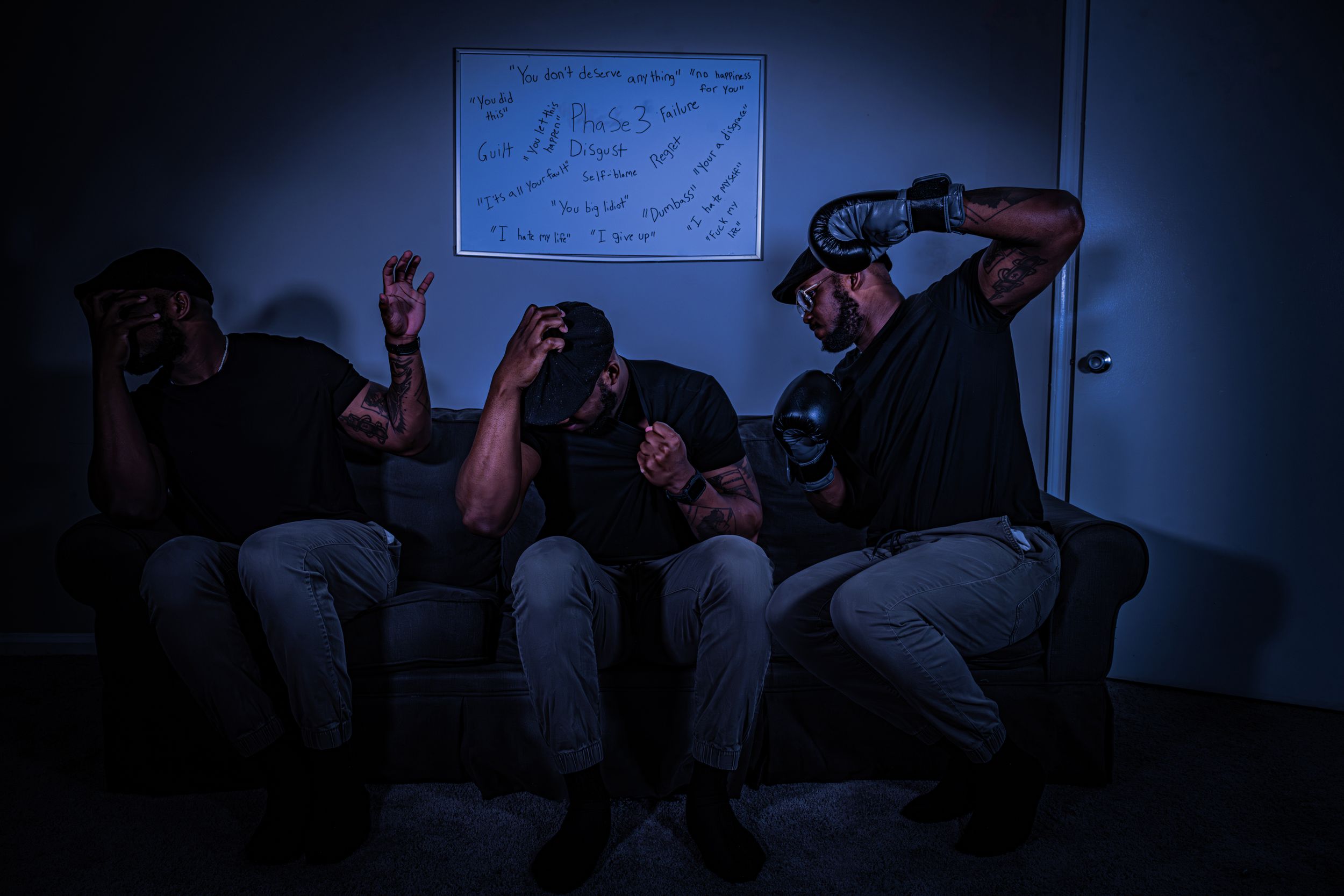 Multiple figures sitting in a blue-tinted room looking down at mobile devices.