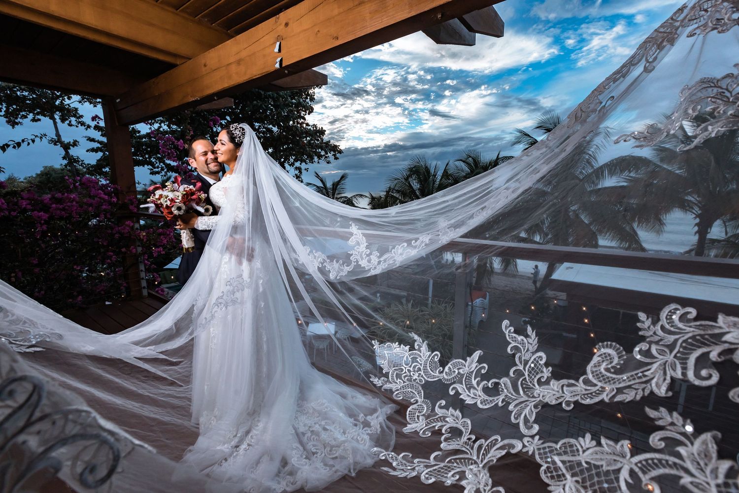Long flowing lace wedding veil with intricate details captured against mountain landscape.