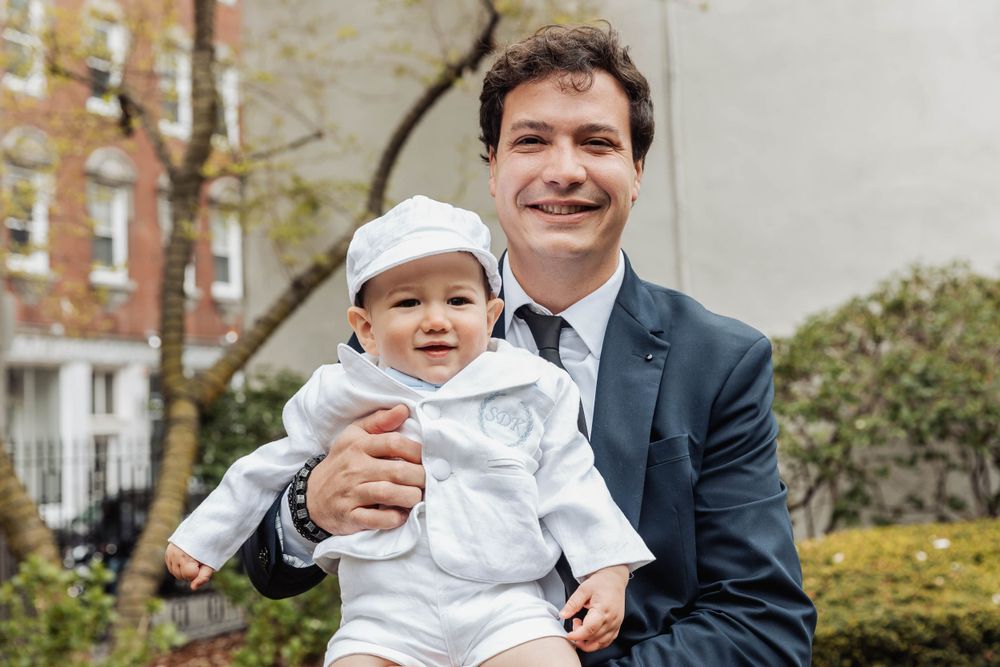 A joyful outdoor portrait in front of brick building and greenery.
