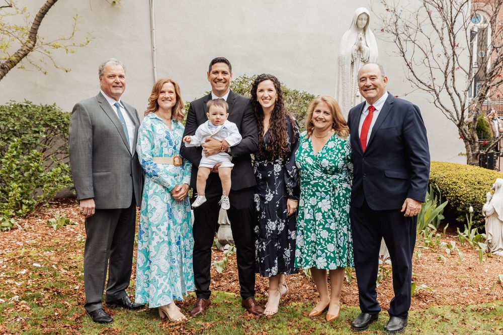 Extended family group portrait in coordinated outfits against garden backdrop.