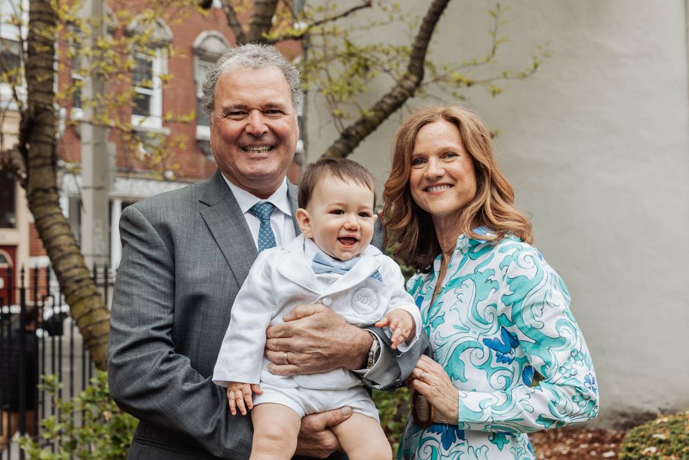 Outdoor family portrait in spring with formal attire against brick building backdrop.