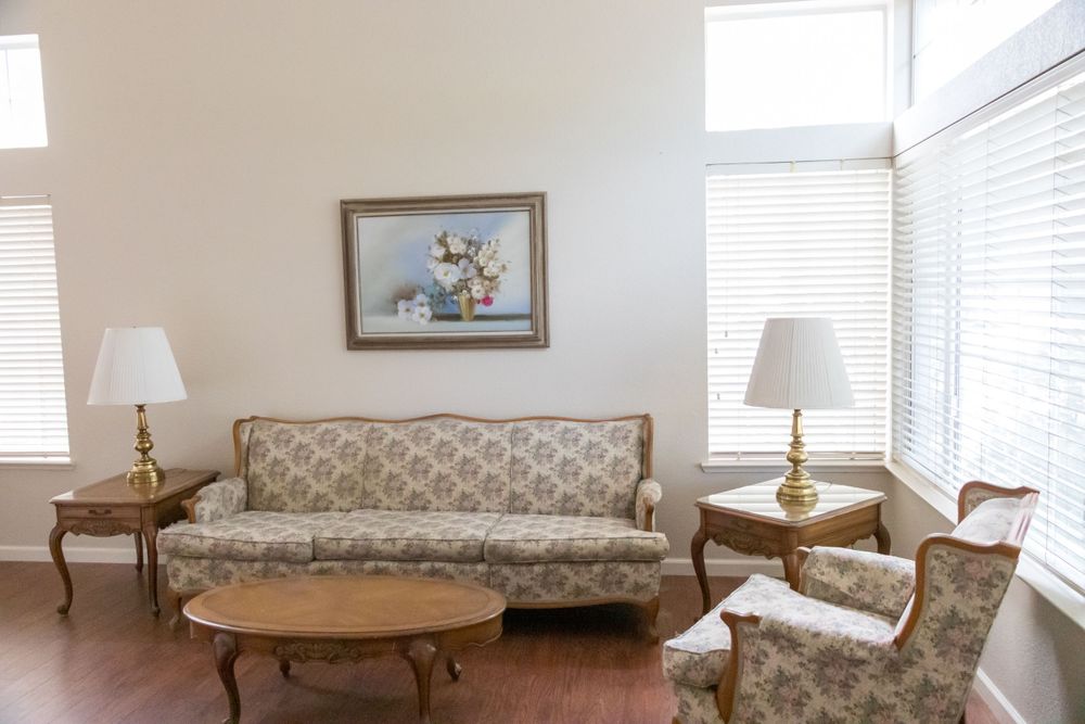 Formal living room with vintage floral sofa, matching chairs, gold table lamps, and round coffee table.