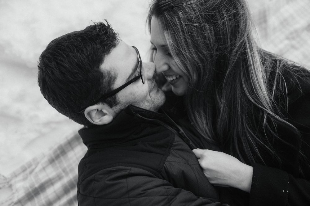Black and white close-up of romantic couple sharing intimate moment in snow.