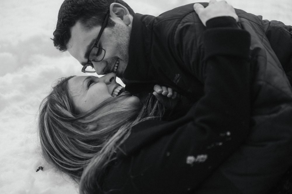 An intimate black and white photograph showing a couple sharing a tender moment in winter.