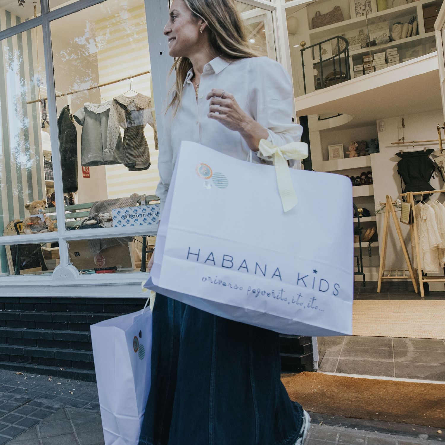 influencer belen Vazquez salındo de Habana Kids con bolsas de compras. marketing de negocios tienda ropa infantil