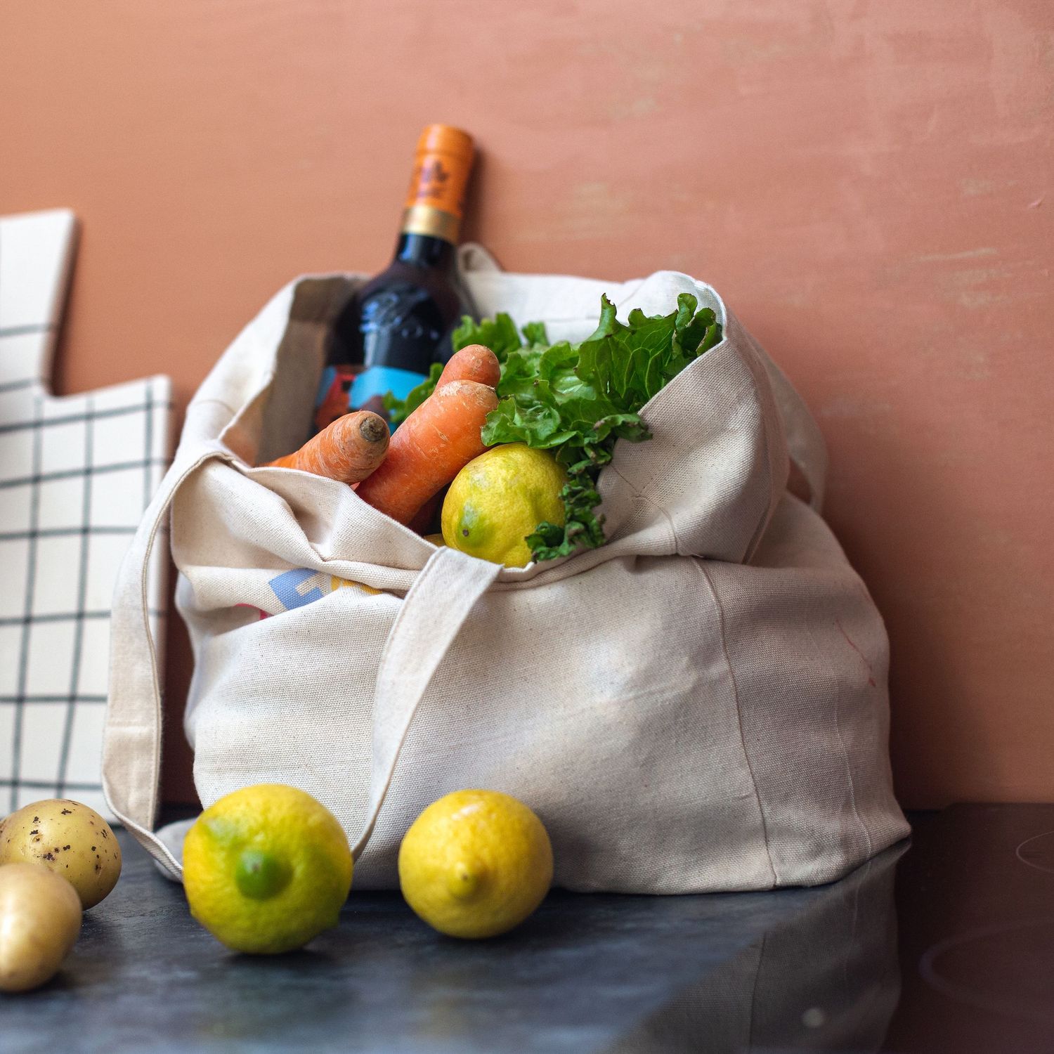 bolsa de tela llena de frutas, verduras y vino. encena cotidiana. sesiones para instagram de catering