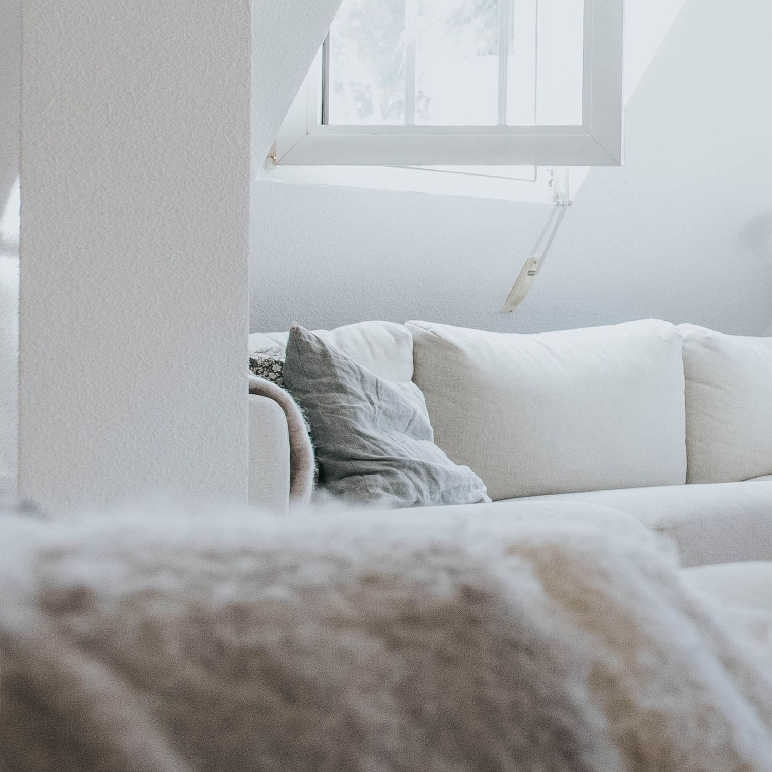arquitectura y interiorismo. salón blanco con mucha luz. sofa y cojín de invierno. foto para empresas