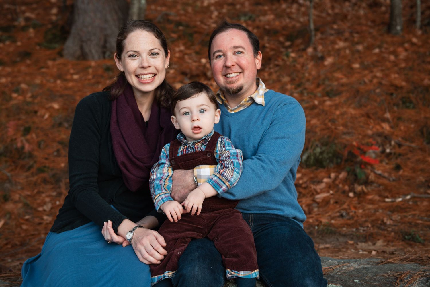 A family poses together for a portrait against a backdrop of orange fall leaves.