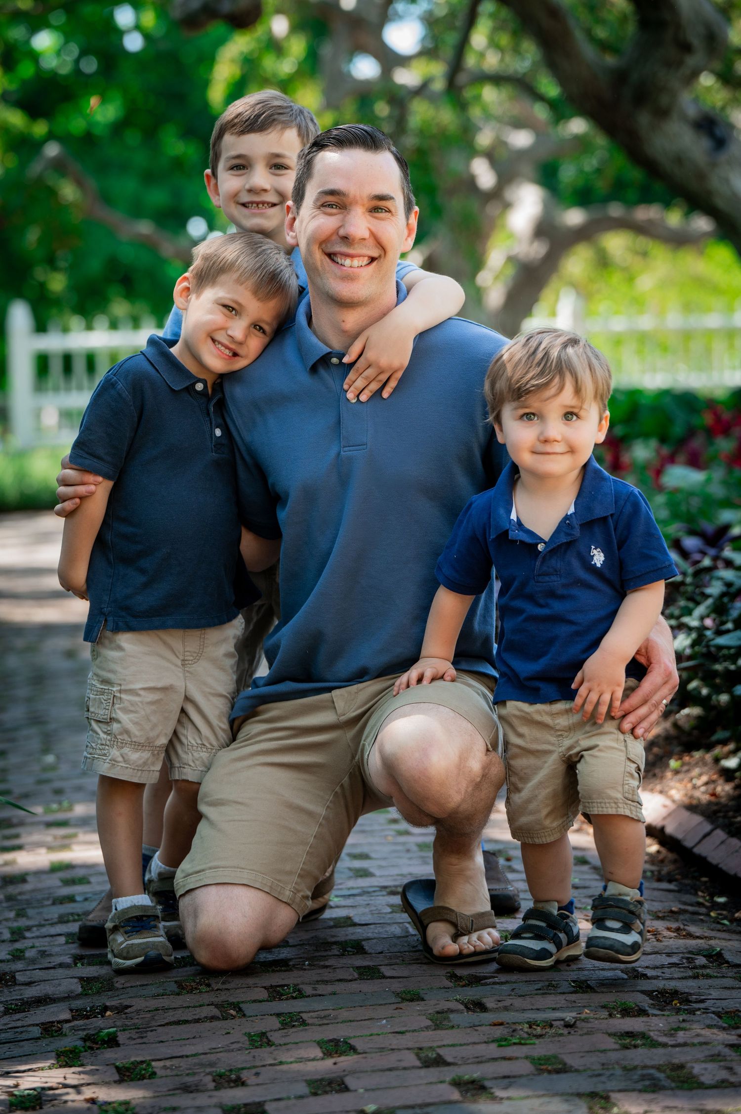A family poses together on a brick pathway in a garden setting. New Hampshire Family Photography Serving New England