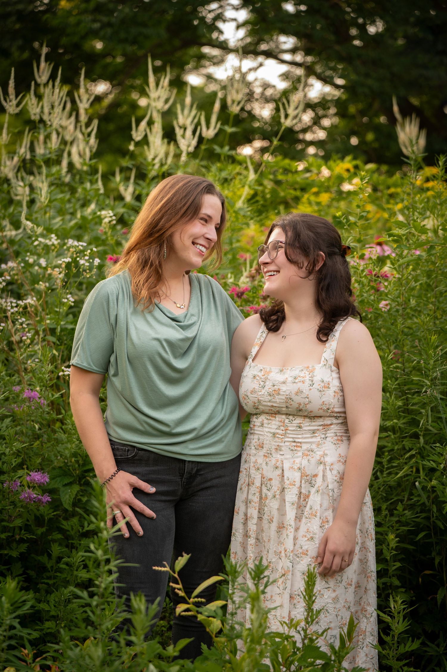 Two people share a joyful moment together in a lush garden setting with wildflowers and greenery. Acton, MA Family photographer Serving