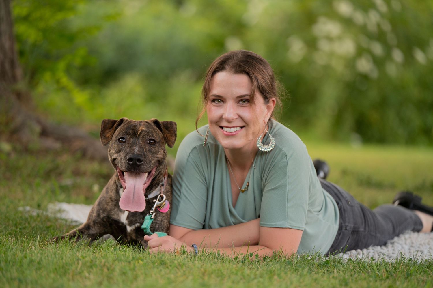 A happy person lies in the grass with their friendly brindle dog on a summer day. Massachusetts Family photographer Serving New England