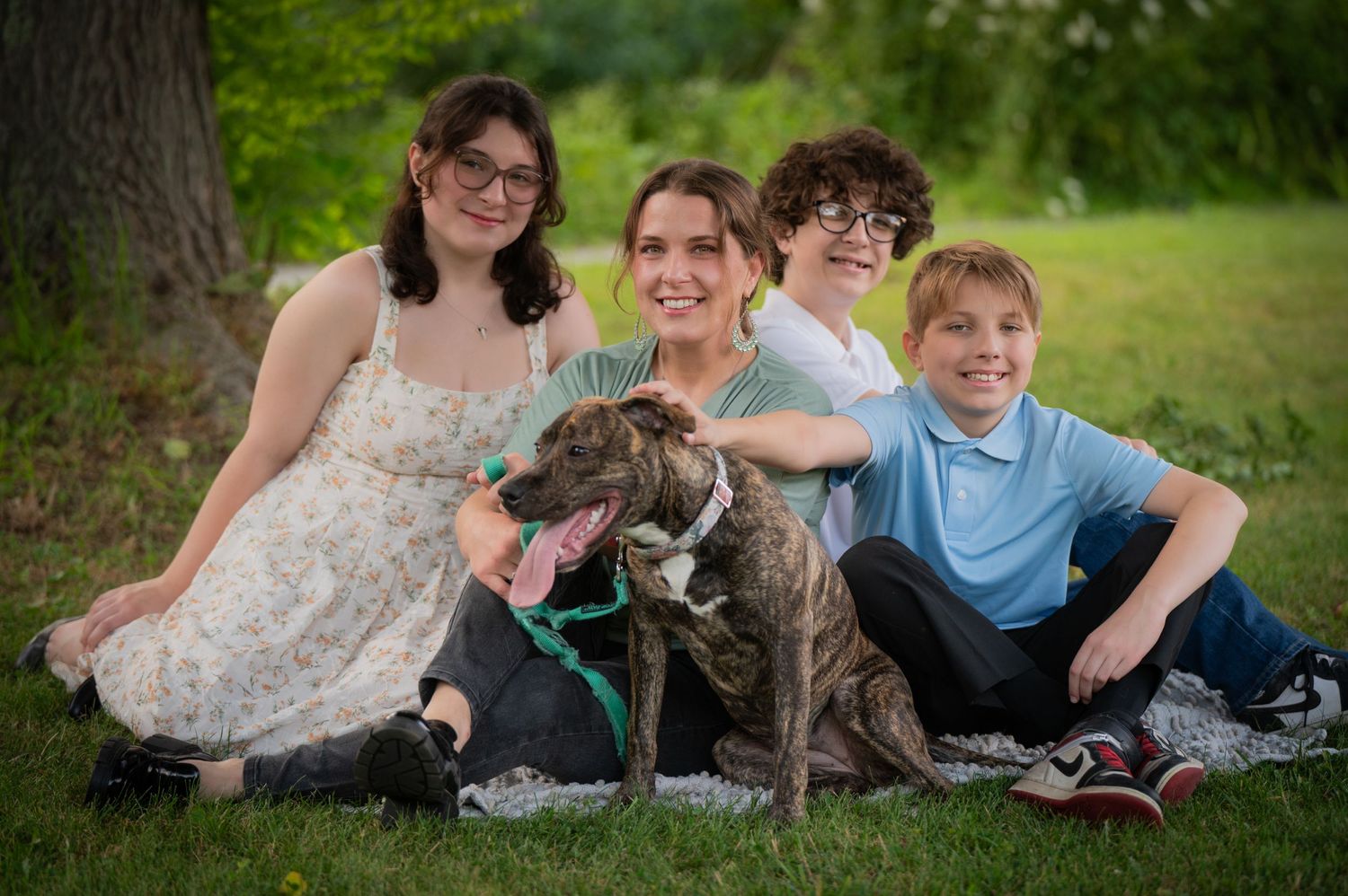 A family and their large brindle dog pose together for a casual outdoor portrait. Massachusetts Family photographer Serving New England