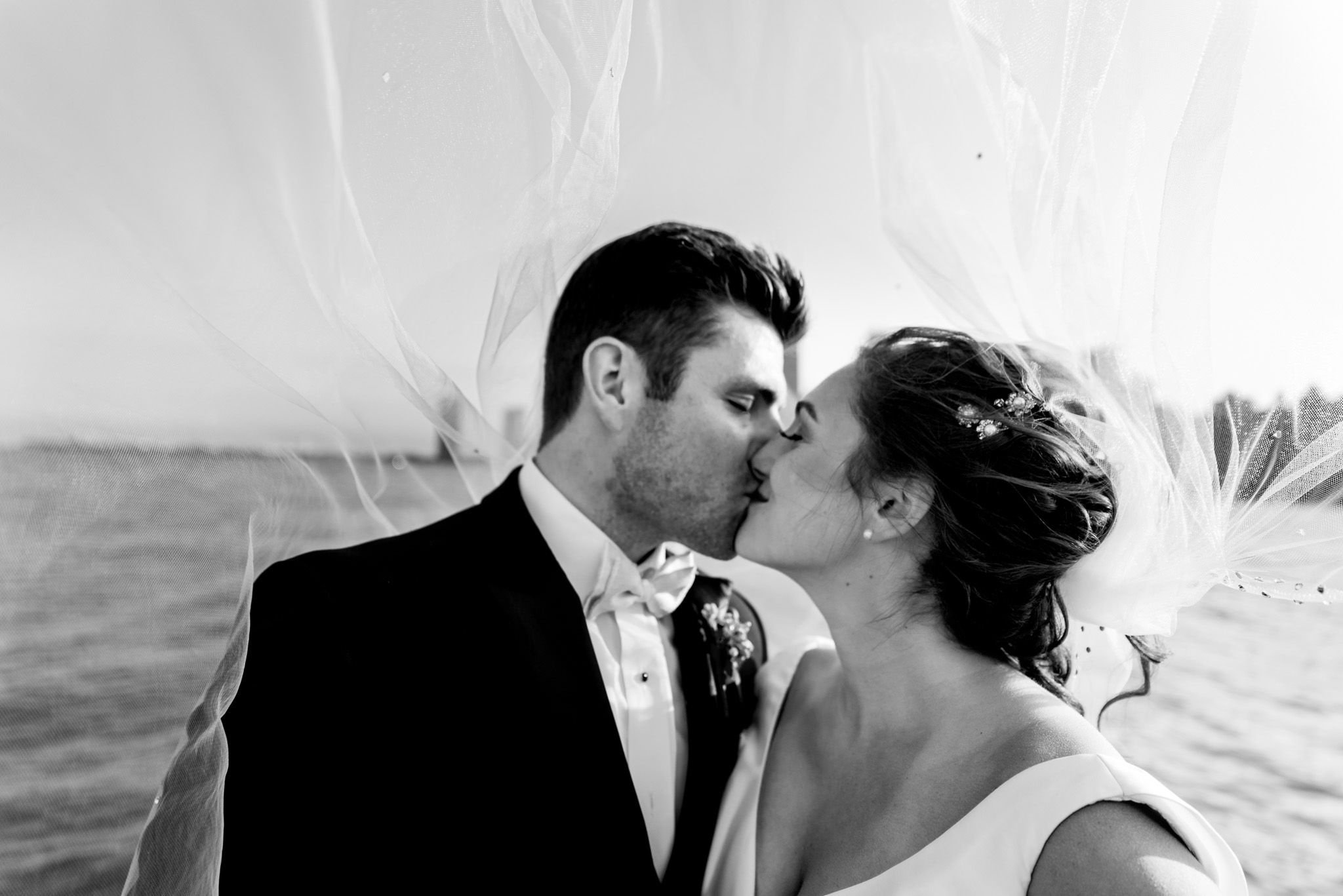 black and white portait of bride and groom kissing in front of chicago skyline