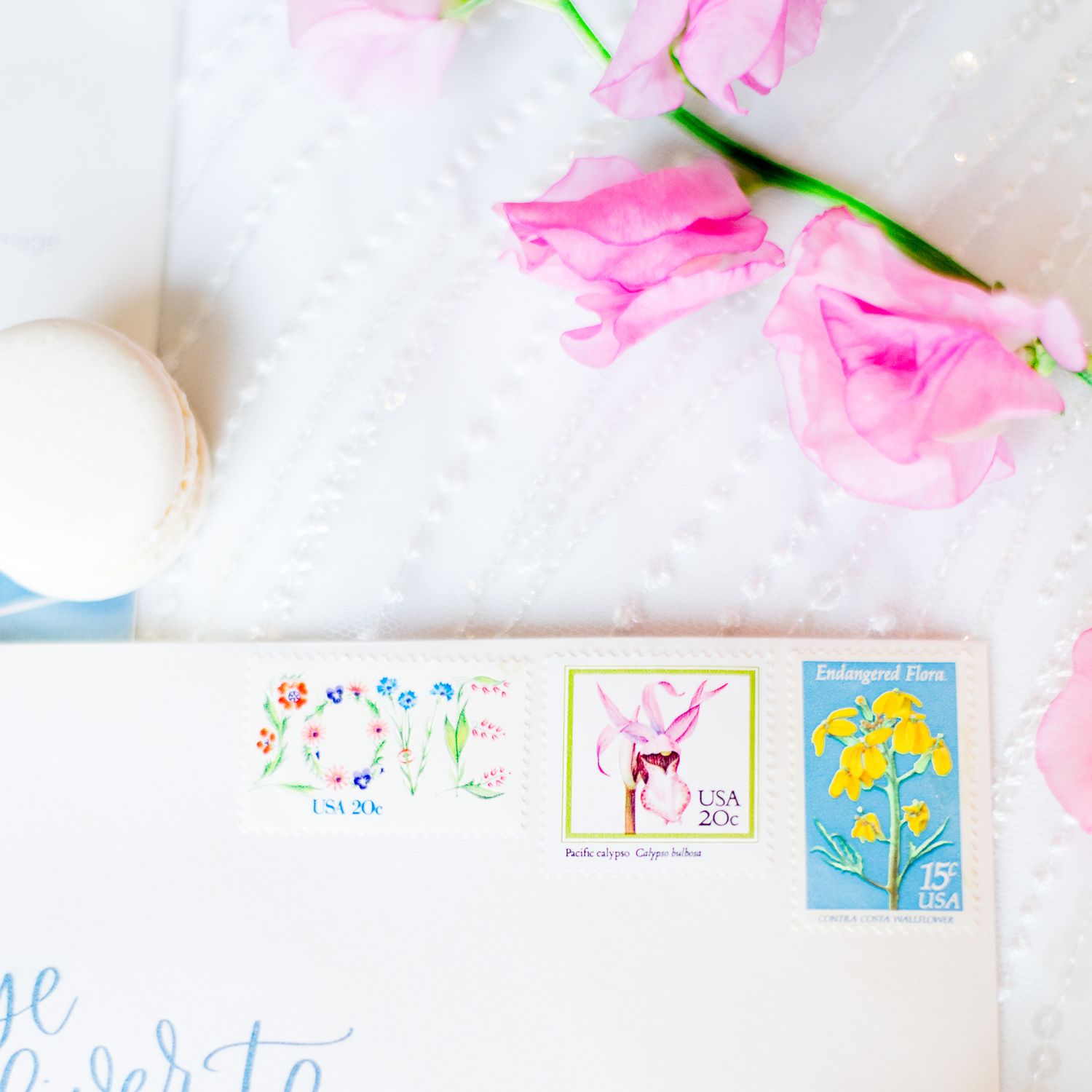 cute colorful floral stamps on envelope and sweet pea flower and macaron next to it