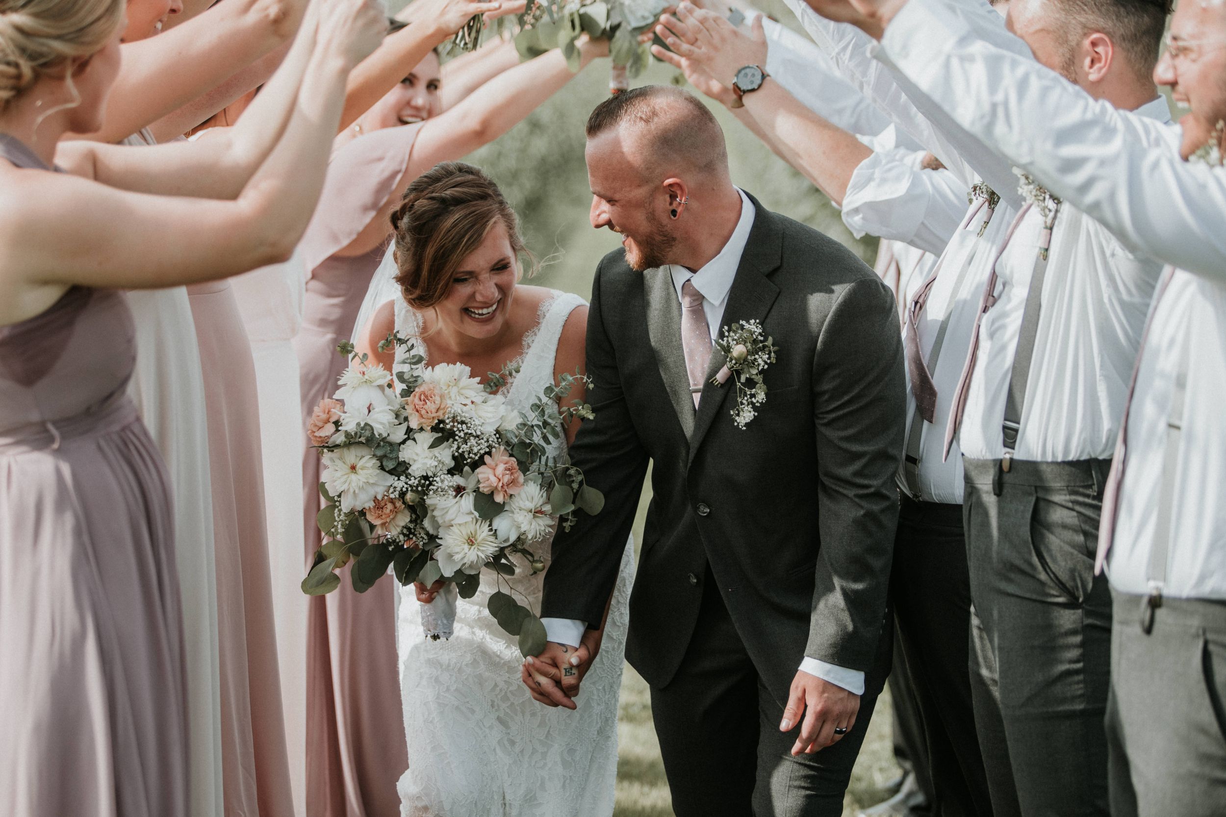 Bride and groom walking through a tunnel of their wedding party