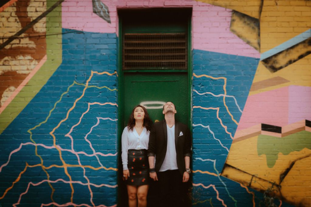 Wedding portraits against colorful painted mural with geometric patterns.