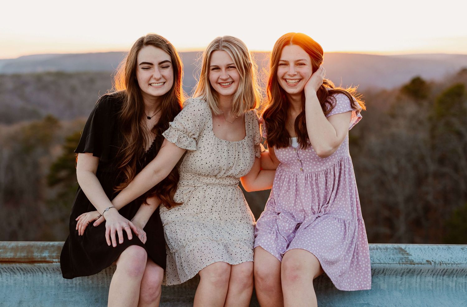 Three girls laughing as the sun sets behind them