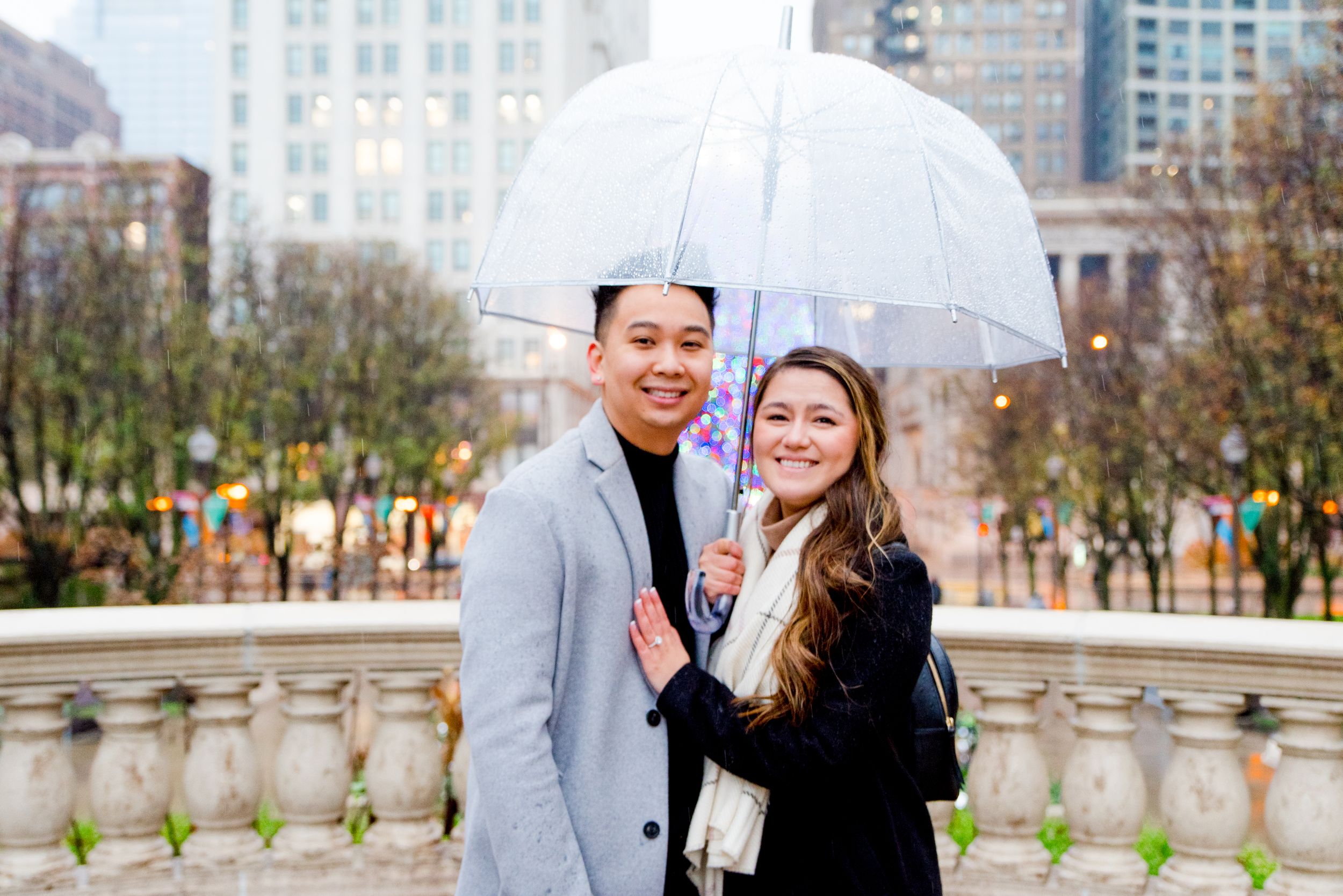 young couple smiling under clear umbrella on rainy day in Chicago after Millennium Park proposal