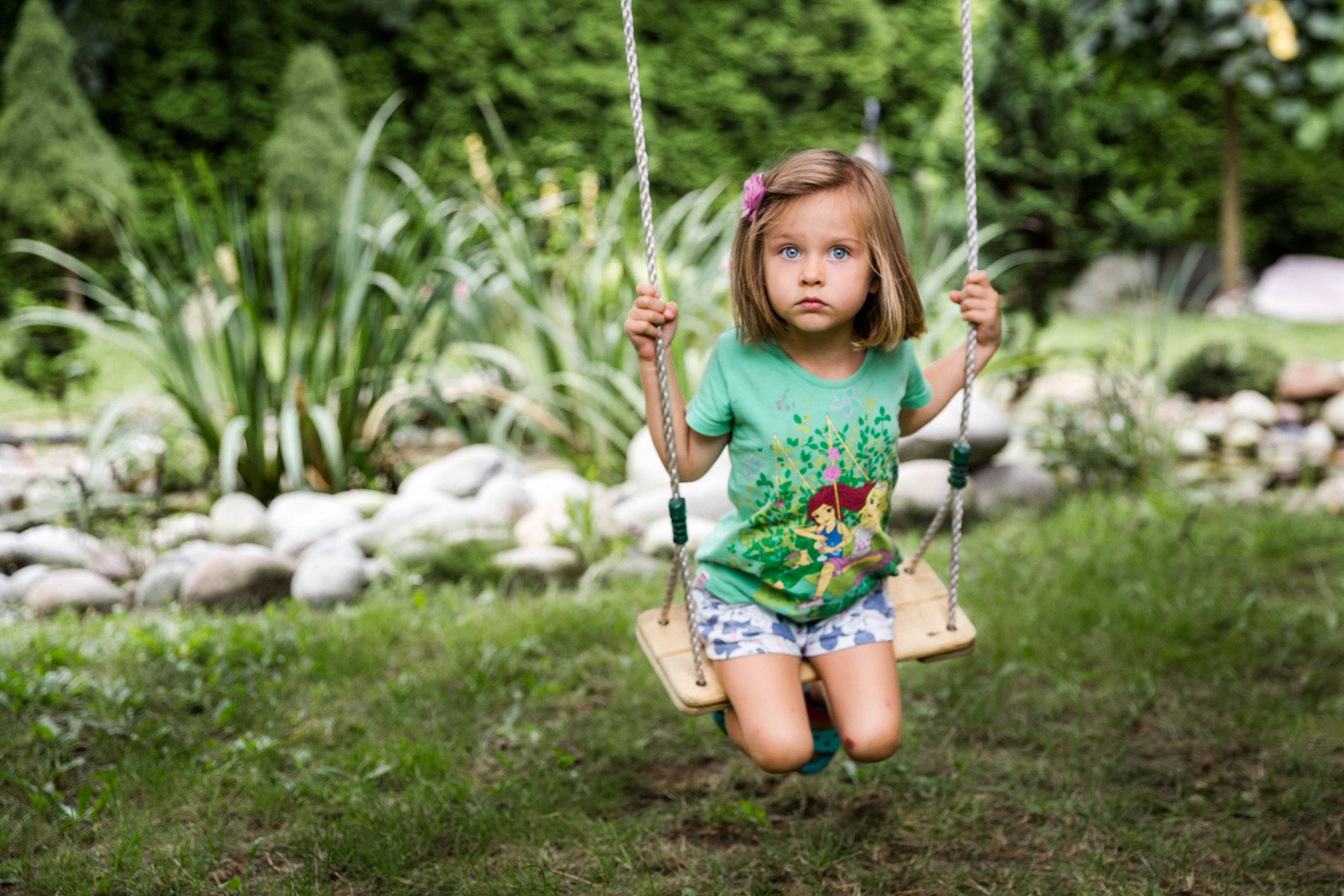 girl in green t-shirt sitting on swing