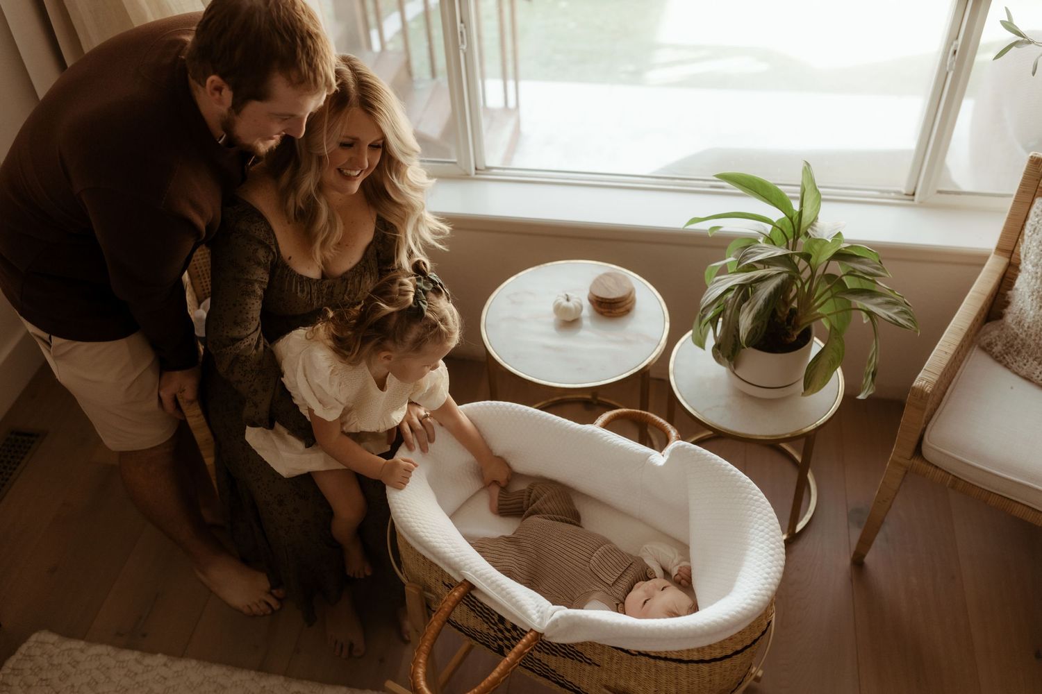 Family looking down at their newborn in his bassinet during their newborn photography session in Erie Colorado