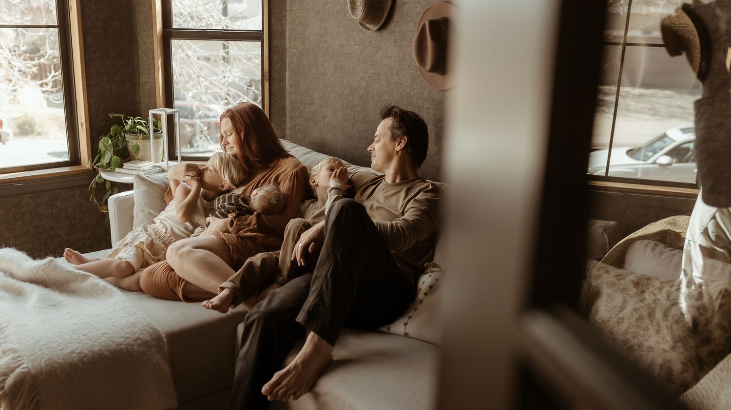 A family relaxing in their living room with their newborn during their motherhood photography session in Longmont CO