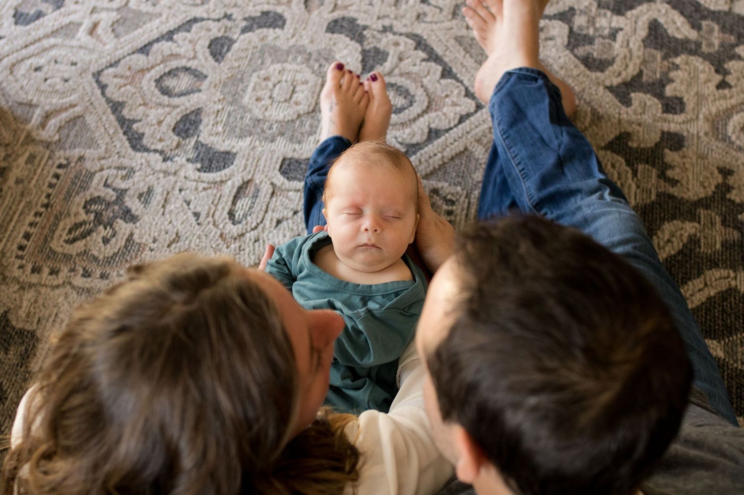 Looking over parent's heads to see their baby in front of them during their Erie, Colorado newborn photo session