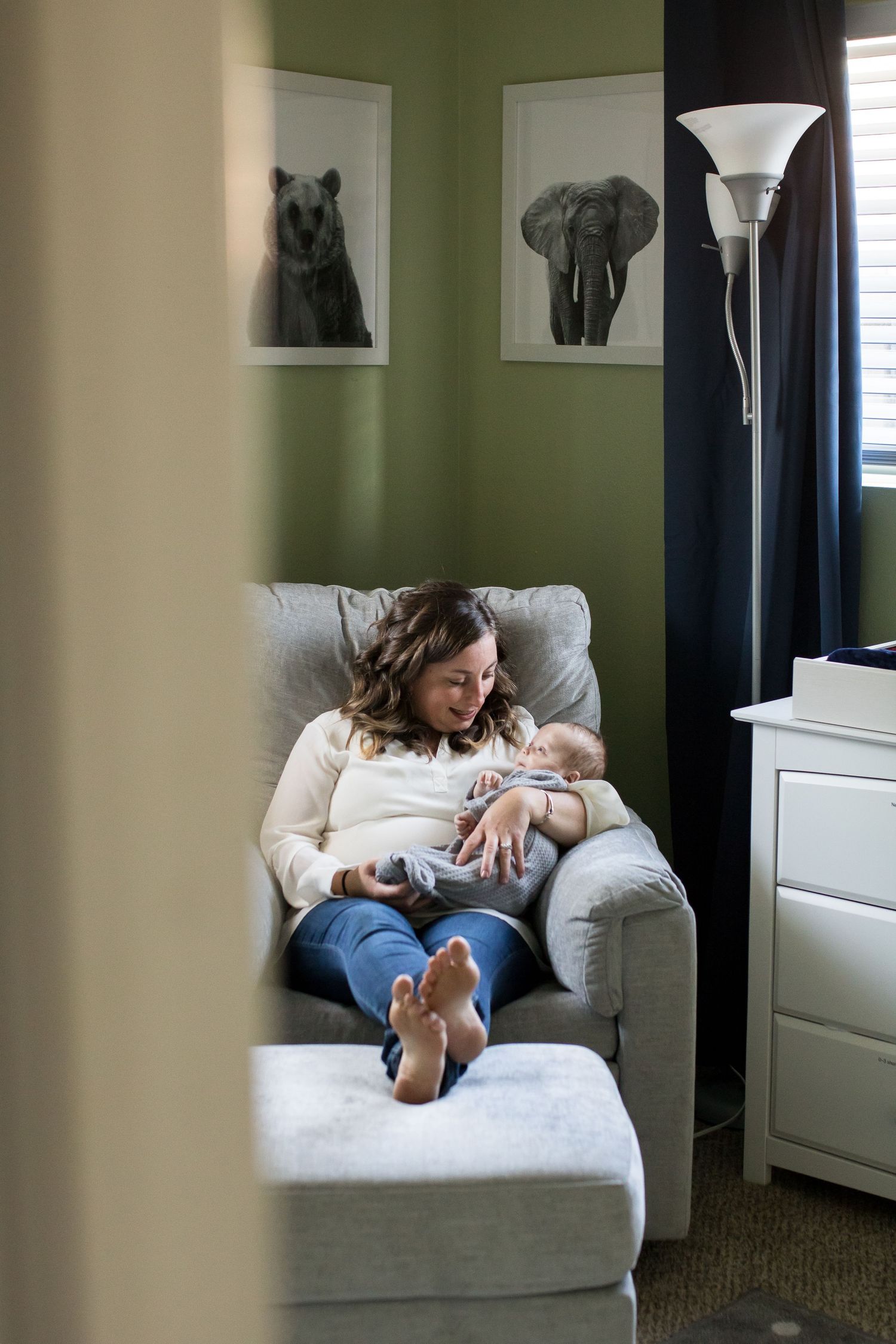 Peeking into the nursery as a mom gazes at her newborn during a newborn photography session in Boulder Colorado