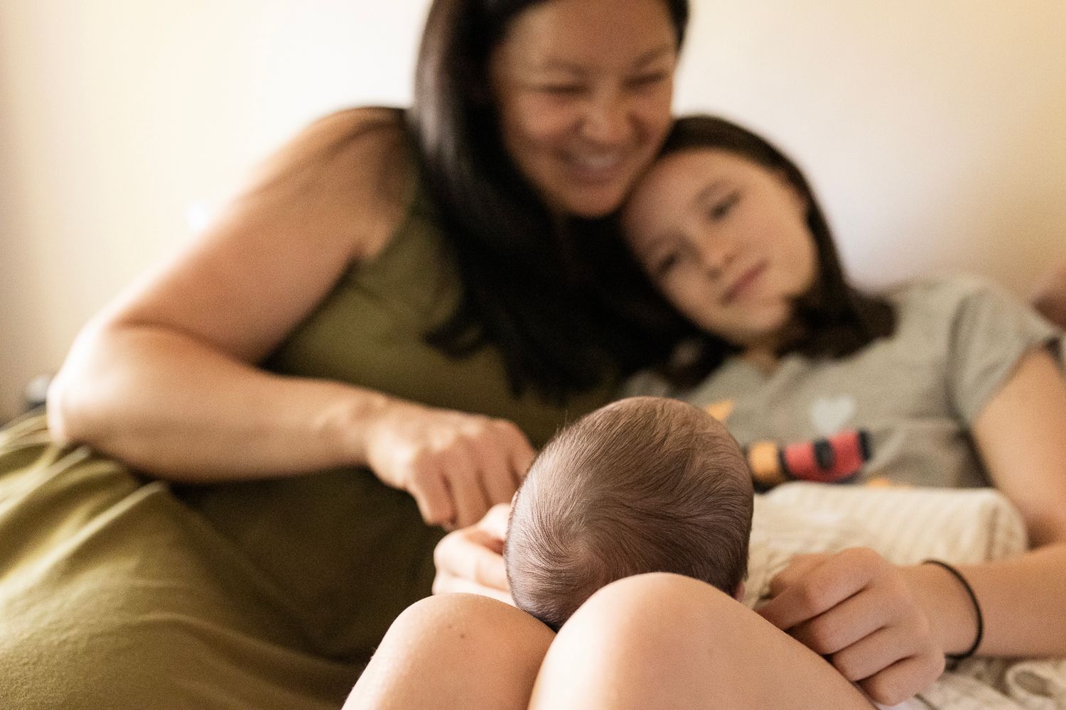 Mom and oldest daughter look at newborn baby during the family newborn photography session in Longmont, CO