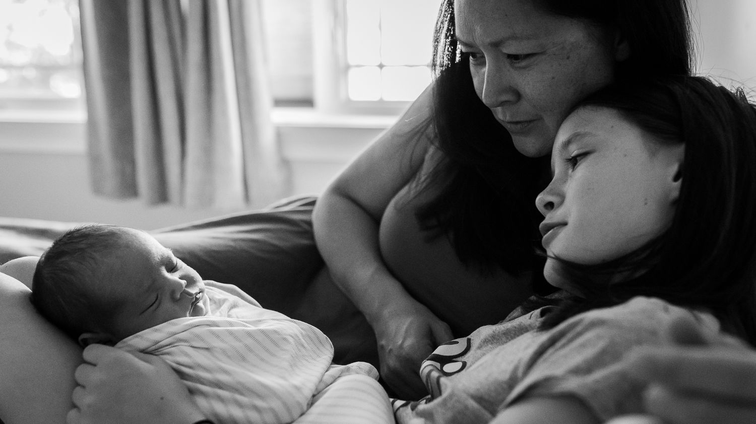 Black and white image of mom snuggling her oldest daughter and newborn son in Longmont, CO