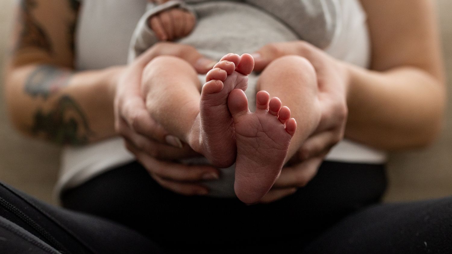Mama holding newborn in lap during their Longmont, Colorado newborn photography session