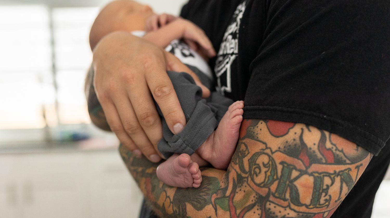 Father holding his newborn during their lifestyle newborn session in Longmont, Colorado.