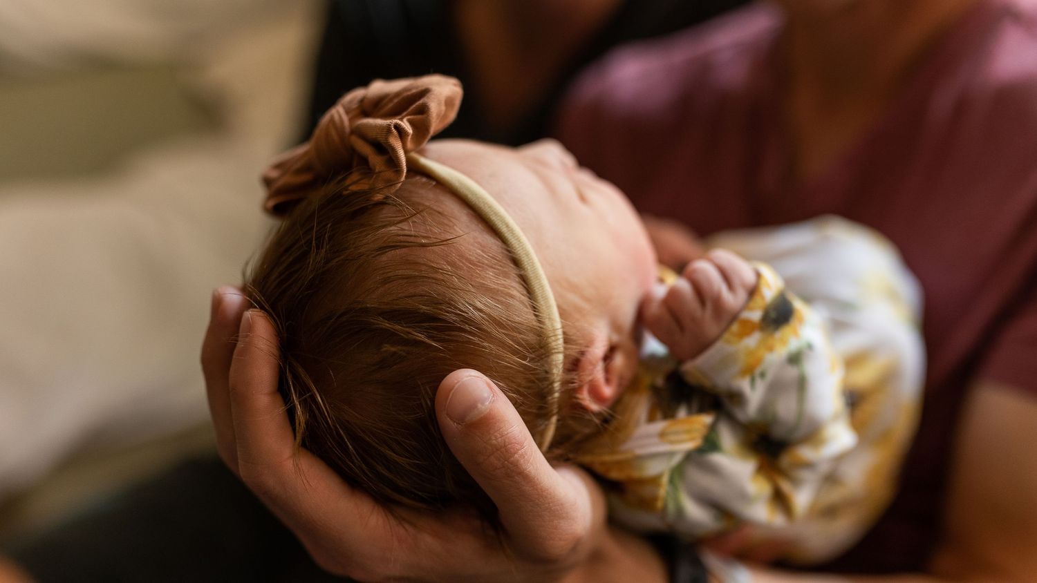 Father cradling his daughters head full of hair during her newborn photography session in Erie, CO