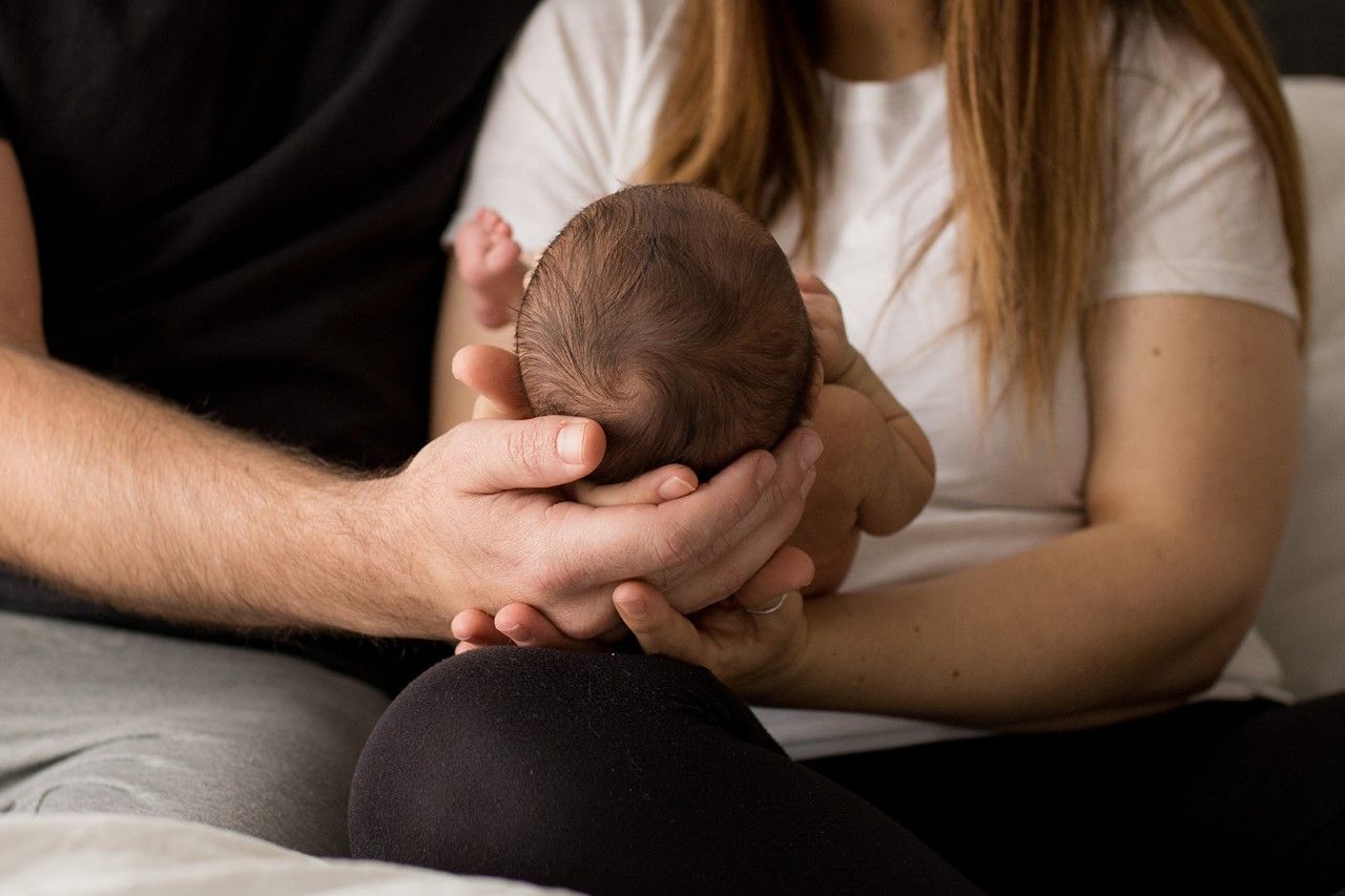 Parents cradling their baby and holding hands during their Boulder, Colorado newborn photography session